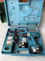 Open carrying case showing cordless drill, two removable batteries, battery charger with cord, and side handle.