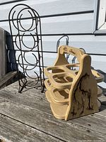 Photo showing the metal wine rack and the wooden wine carrier with tree burn design side by side outdoors on a wooden surface.