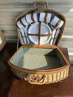 Open wicker picnic basket showing interior lining and attached tableware