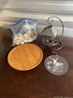Overview photo showing the lantern, wooden plate, seashell bag and wildlife plaque on a table.