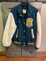 Front view of green wool body varsity jacket with white leather sleeves and Spartans logo patch.