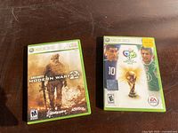 Two Xbox 360 game cases side by side showing the front covers of Call of Duty: Modern Warfare 2 and 2006 FIFA World Cup.