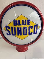 Front view showing Blue Sunoco logo on glass globe, red metal rim and base