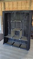 Portable closet open, showing six fabric shelves and metal frame structure inside.