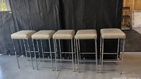 All five chrome bar stools arranged in a row against a black backdrop