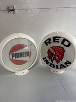 Front view of both globes showing Pioneer logo (left) and Red Indian graphic (right) on glass faces