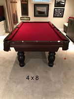 Assembled pool table showing red felt surface, turned legs, and leather drop pockets