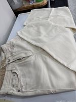 Full view of cream-colored rag & bone cotton jeans laid flat showing front pocket, waistband and leg.