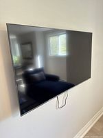 Front view of mounted TV on wall with power cable visible