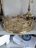 Close up side view of brass tray showing camel cut-out motif around rim
