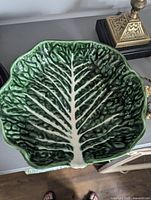 Close-up of a green cabbage leaf ceramic plate showing detailed veining and glossy finish.