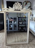 Front view of rectangular mirror with cream composite frame and decorative shell motif top
