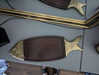 Full view of the fish shaped serving tray showing the wooden surface and brass head and tail detailing.