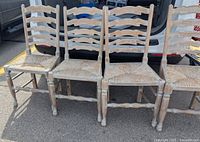 Four whitewashed ladder-back chairs arranged side by side, front view