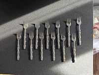 Twelve forks displayed laid out flat on a dark surface, showing the overall set and bamboo motif handles.
