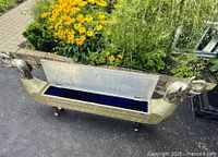 Overall view of long rectangular metal bench with open hinged lid and blue velvet interior