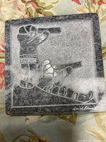 Front view of gray marble sculpture showing design of two hands pointing in different directions, signed David Bennett.