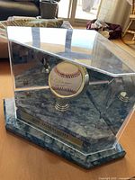 Overall view of baseball in acrylic display case on faux marble base
