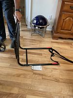 Side view of black foldable metal bed rail fitted with adjustable safety strap and label.