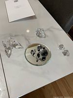 Photo of all crystal figurines on white marble surface showing butterflies, pandas on mirror base, and birds.