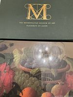 Box and single placemat showing fruit basket still life design, cork-backed by Jason for The Metropolitan Museum of Art.