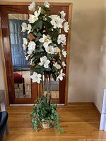 Front full view of artificial magnolia tree standing tall in room with wooden floor and mirrored doors behind