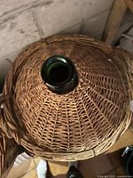 Top view showing woven basket surrounding the neck of green glass demijohn.