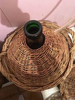 Top view of the narrow neck of the green glass demijohn inside the woven wicker basket cover.