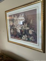 Side angled view of framed flower print showing gold ornate frame, matting and flower artwork.