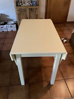 Front view of the off-white extendable table in a closed position with the leaves retracted.