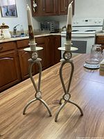 Pair of metal candle holders with decorative glass spheres and taper candles on wooden table in kitchen setting