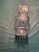 Top view of glass decanter with stopper in place showing square shape and ridged design.