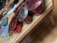 Five small metal planters displayed on a wooden table, showing variety in color and decorative finishes