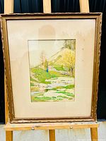 Full view of the framed watercolour painting showing the countryside landscape with a hill, trees and a river.