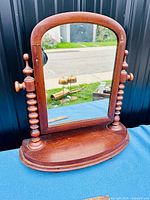 Front view of antique wooden dressing table mirror showing rounded top, turned wooden supports and oval base.