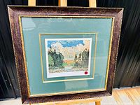 Framed limited edition print 'Black Spruce in Autumn' by Tom Thomson in a mottled dark wood frame with green and gold matting, behind glass.