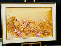 Full view of the framed painting showing two faces in a floral field, with warm earth tone colors and accents of pink and white flowers.