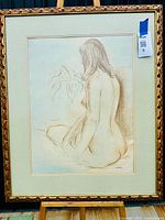 Full view of the framed chalk drawing showing the nude woman seated with back turned, near a plant.
