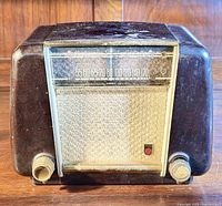 Front view of vintage Phillips tube radio showing Bakelite case, speaker grille, frequency dial, and two control knobs.