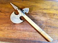 Full view of vintage style battle axe showing wooden handle with multiple carved details and multi-blade metal head with a spear tip, large axe blade and smaller blade.
