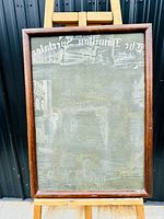 Framed print block showing reversed text and images from the Hamilton Spectator newspaper, mounted on an easel.
