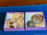 Baroque pearl necklace with irregular-shaped pearls in cream and pink hues, sterling silver clasp, placed in a purple box on a blue velvet surface.