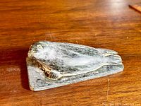 Front and side view showing the seal sculpture resting on its base on a wooden surface.