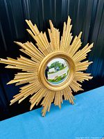 Front view of large golden sunburst mirror with convex central glass showing overall design and condition.