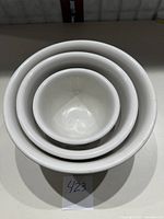 Stacked view of the three nested white ceramic mixing bowls showing their relative sizes and smooth surfaces.