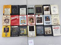 Top view of 21 different 8-track cartridges showing front labels with album art and artists, various colors and designs.