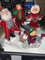 Four felt Annalee dolls posed together showing full set, including Santa, Mrs. Claus, and two elves with holiday-themed outfits and accessories.