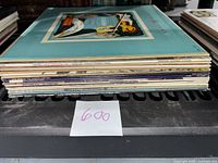 Side view of stacked vinyl albums showing approximately 16 albums.