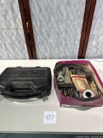 Closed carrying case labeled Black & Decker alongside an open box with tools and accessories including solder and wires.