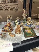 Multiple assorted Boyds Bears and Friends figurines displayed on table including both bears and a woman holding child.